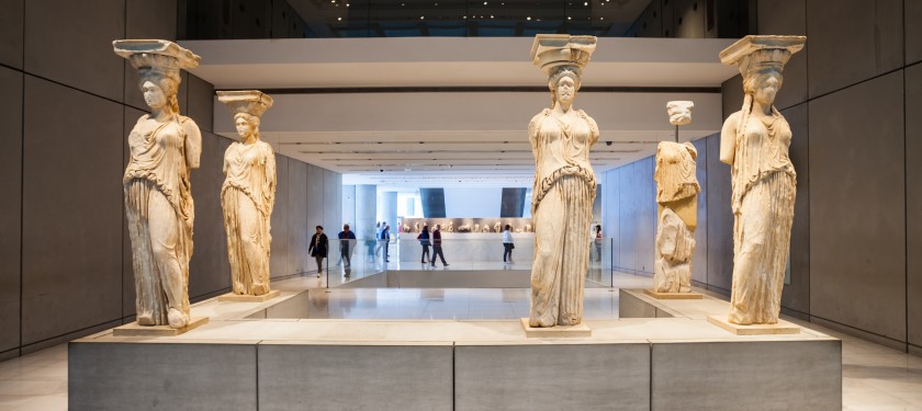Cztery kariatydy, posągi kobiet trzymające na głowie elementy architektury, jedna mocno uszkodzona, widoczne w muzeum